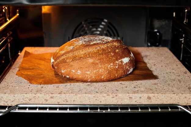 Homemade round rye bread is baked in the oven on a baking stone