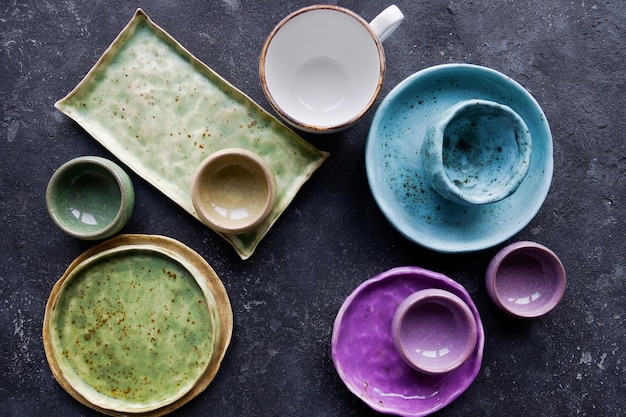 Фото Домашняя деревенская посуда красочные керамические тарелки и миски на темном каменном бетонном фоне уютная концепция кухни вид сверху избирательный фокус