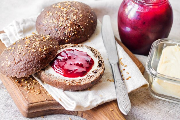 Homemade rye buns with linseeds, sesame and white poppy seeds served with butter and jam