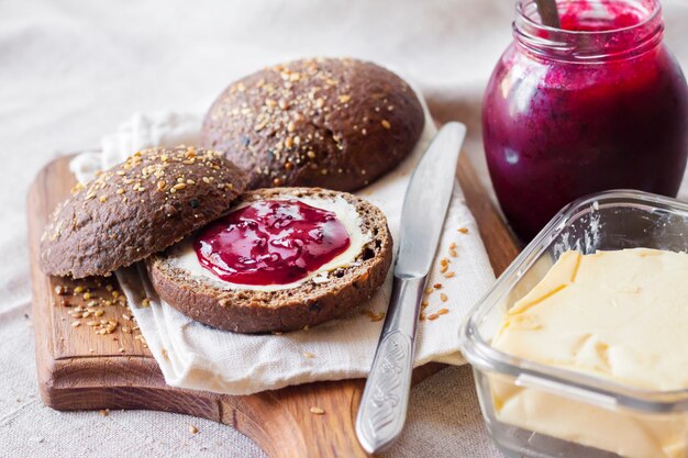 Homemade rye buns with linseeds, sesame and white poppy seeds served with butter and Jostaberry jam