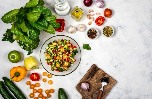 Homemade salad from various organic vegetables in a glass bowl with ingredients and spices