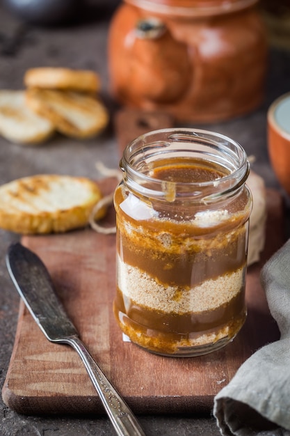 Homemade salted caramel sauce with cookies in jar on rustic background.