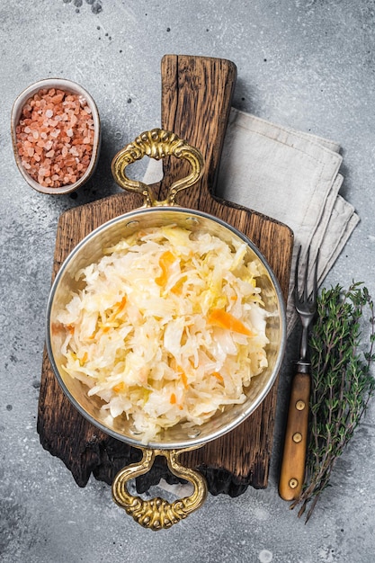 Homemade sauerkraut with black pepper and salt in a skillet. Gray background. Top view.