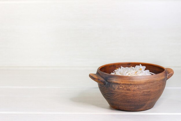 Homemade sauerkraut with carrots in bowl on wooden background with copy space.