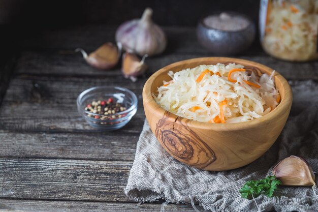 Homemade sauerkraut with carrots in a bowl on wooden rustic table. Vegetarian vegan food.