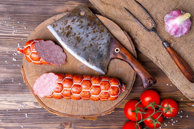 Homemade sausage cut in half on a wooden background. Vegetables and kitchen accessories, top view