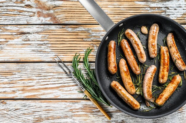 Homemade sausages fried in a pan, beef and pork meat. wooden background. Top view. Copy space.