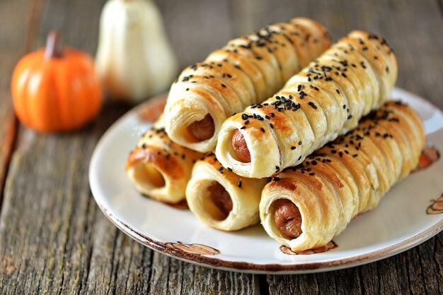 Homemade sausages in puff pastry on wooden background