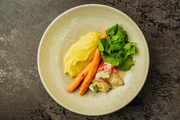 Homemade sausages with mashed potatoes and vegetable salad served on a plate at the restaurant top view