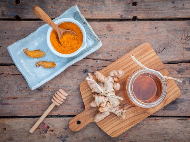 Homemade scrubs honey and curcumin roots setup on old wooden table.