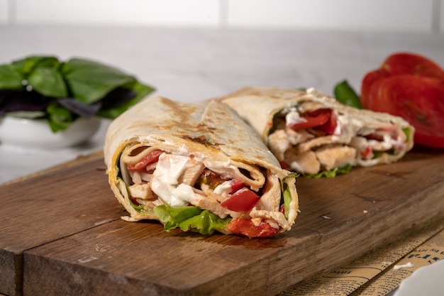 Homemade shawarma or burrito or chicken roll with vegetables and sauce