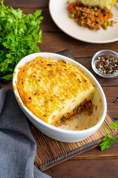 Homemade shepherds pie in the casserole dish on a dark wooden\
background