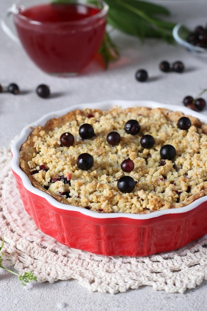 Homemade shortbread cake with black currant in a ceramic form on a gray background