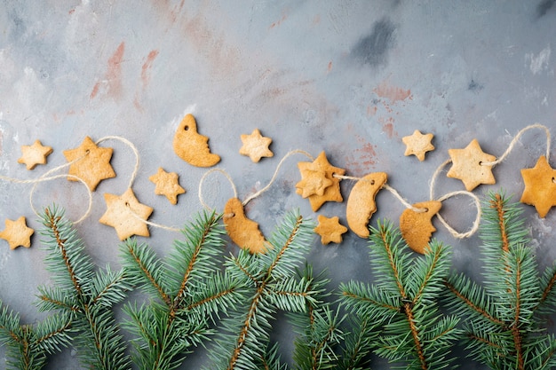 Homemade shortbread star shape sugar with sugar powder and branch of fit-tree on thread over blue texture surface.  Christmas or New Year. Top view with space.