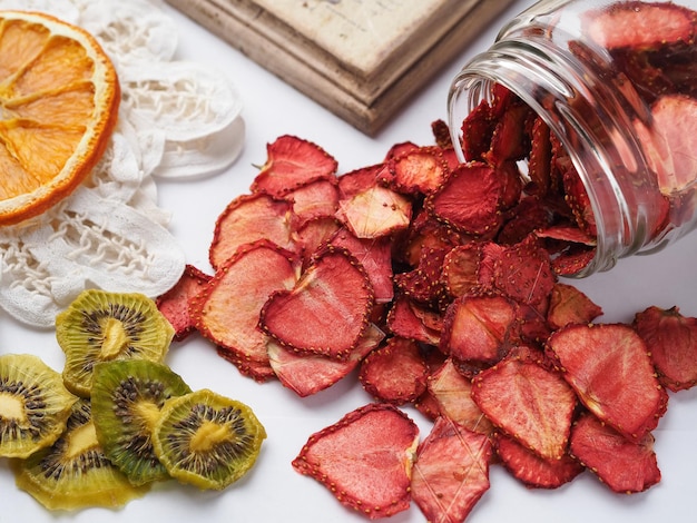 Homemade slices of dried oranges, strawberry and kiwi on white background, top view.