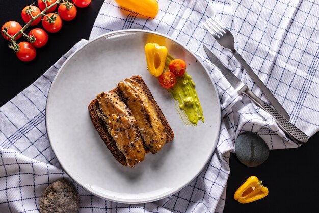 Homemade smoked herring sandwich with rye bread on light grey plate, top view