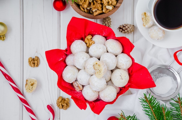 白い木製のテーブルの上にボウルに砂糖をアイシングでクルミと自家製雪玉クッキー