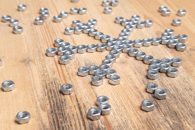 Homemade snowflake made of metal nuts on a wooden table