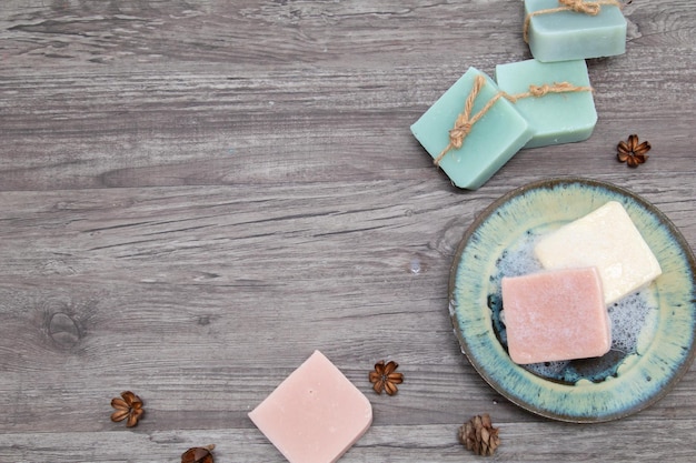 Foto concetto di sapone fatto in casa con spazio copia, fatto a mano biologico con oli, ingredienti a base di erbe e lavanda, trattamento termale aromatico naturale su sfondo vintage in legno, sapone schiumoso bagnato su piastra