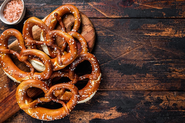 Homemade Soft Pretzels with Salt on a wooden board. Dark wooden background. Top view. Copy space.