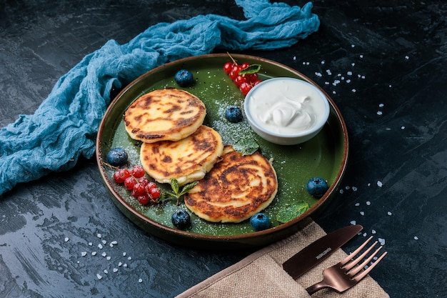 Homemade sottage cheese pancakes syrniki with blueberry in craft green plate