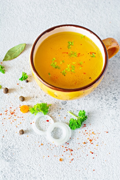 Homemade soup with chicken, vegetables, spices, and herbs in a bowl