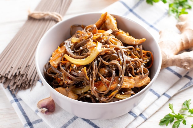 Tagliatella di soba di pollo piccante fatta in casa su un piatto grigio su un tavolo