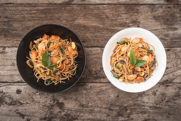 Homemade Spicy Sausage Spaghetti with basil on the plate on the wooden table, Thai style