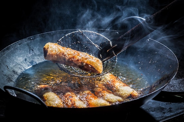 Homemade spring rolls frying in hot oil