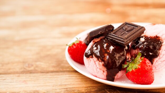 写真 自家製のイチゴアイスクリーム 白い皿に田舎風の背景で チョコレートとイチゴで飾られたデザート