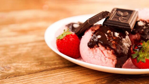 Homemade strawberry ice cream on white plate on a rustic background dessert decorated with chocolate and strawberries