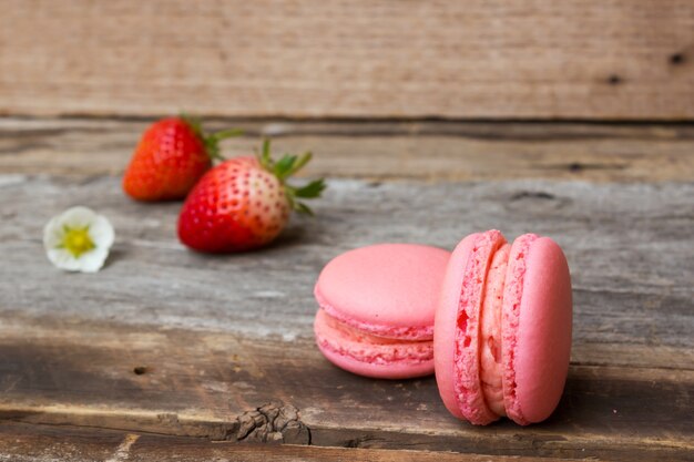 Homemade strawberry macaroons on wooden background.