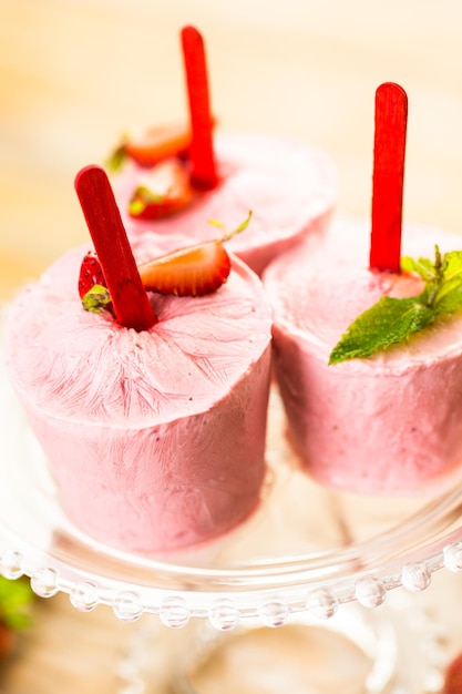 Homemade strawberry popsicles made in plastic cups.