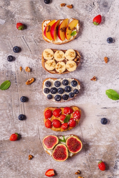 Homemade summer toast with cream cheese, nut butter and fruits and berries, top view.