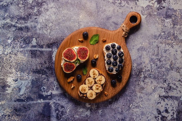 Homemade summer toast with cream cheese nut butter and fruits and berries top view