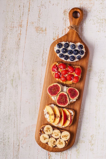 Photo homemade summer toast with cream cheese, nut butter and fruits and berries, top view.