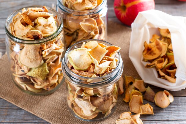 Homemade sun-dried organic apple slices, crispy apple chips, on an old rustic wooden table with fresh apple. Healthy eating. Vitamins.