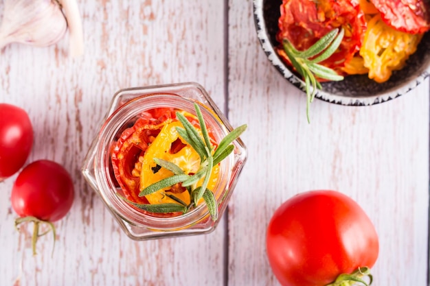 Homemade sundried tomatoes with spices garlic and herbs in a jar and fresh vegetables Top view