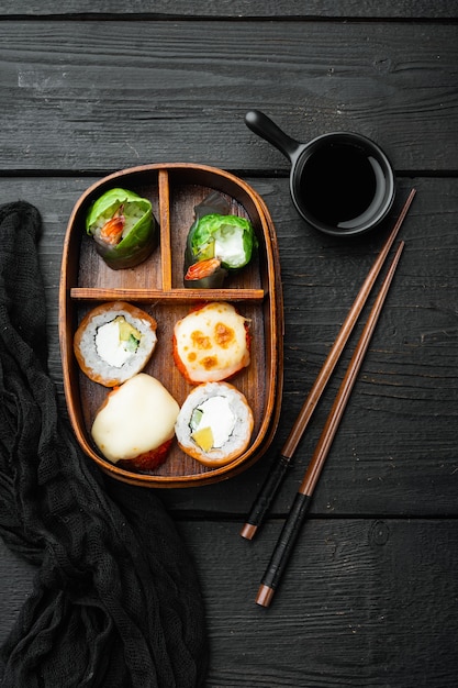 검은 나무 테이블에 스시 롤 세트로 만든 초밥 도시락 상자