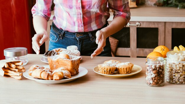 Foto panetteria dolce fatta in casa. stilista del cibo. piatti di organizzazione femminile con pasticcini freschi e vasetti con noci sul tavolo.