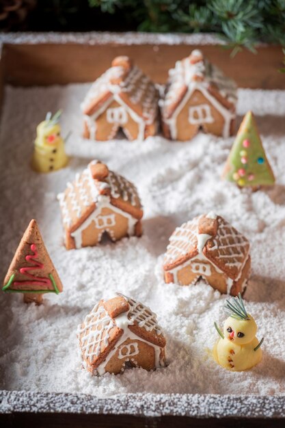 雪だるまと木々のある自家製の甘いクリスマスジンジャーブレッドの村