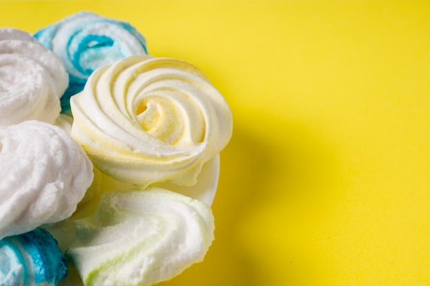 Homemade sweet colored meringue on yellow background.  Dessert.