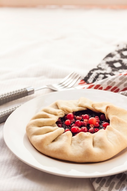 Homemade sweet galette with elderberries and cowberries on a plate.