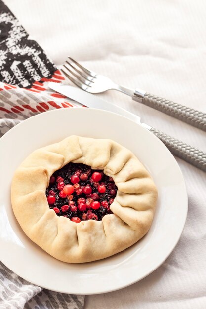 Homemade sweet galette with elderberries and cowberries on a plate