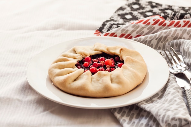 Homemade sweet galette with elderberries and cowberries on a plate