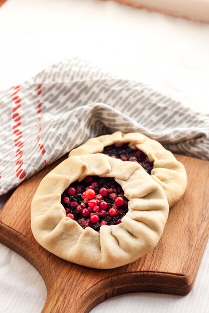 Homemade sweet galette with elderberries and cowberries on a wooden board