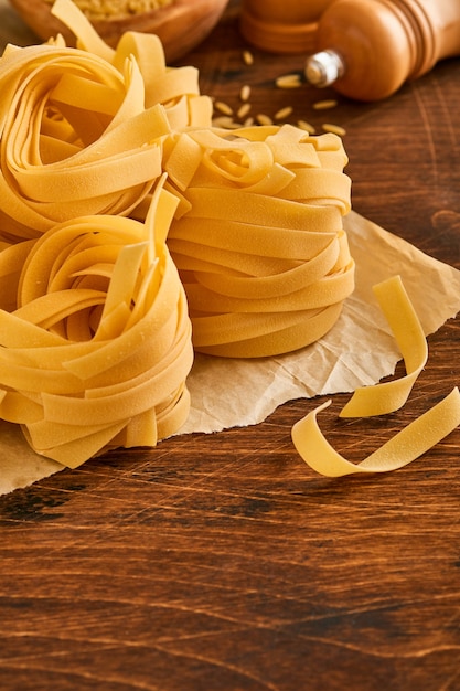 Homemade tagliatelle pasta in brown paper on an old wooden background