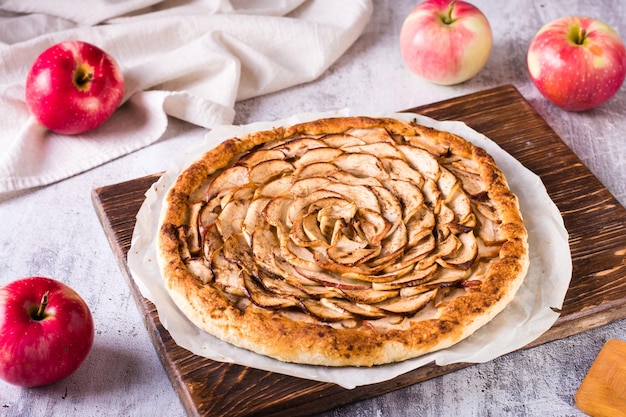 Homemade tart with red apples on baking paper on the table