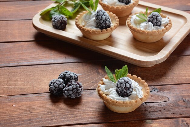 Homemade tartlets with blackberry, whipped cream and mint