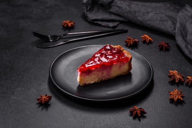 Homemade tasty cheesecake with jelly and raspberry berries on a black plate